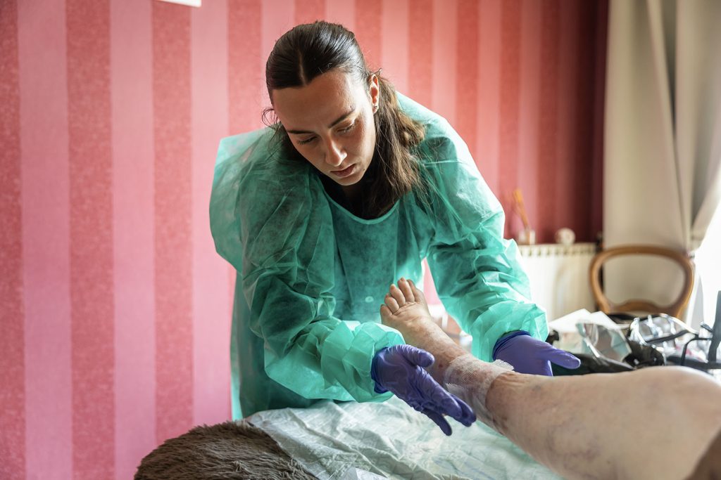 Soignante réalisant un pansement complexe à domicile